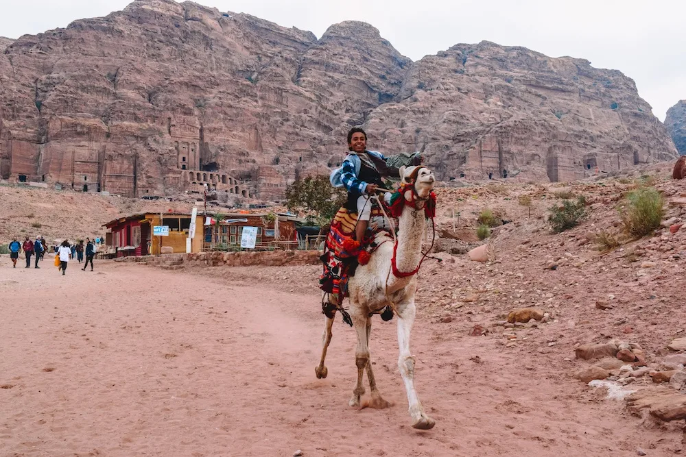 A local kid riding a camel in Petra, Jordan