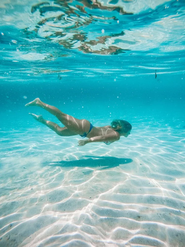 Underwater GoPro shot of a girl swimming in the crystal clear water of Malcapuya Island