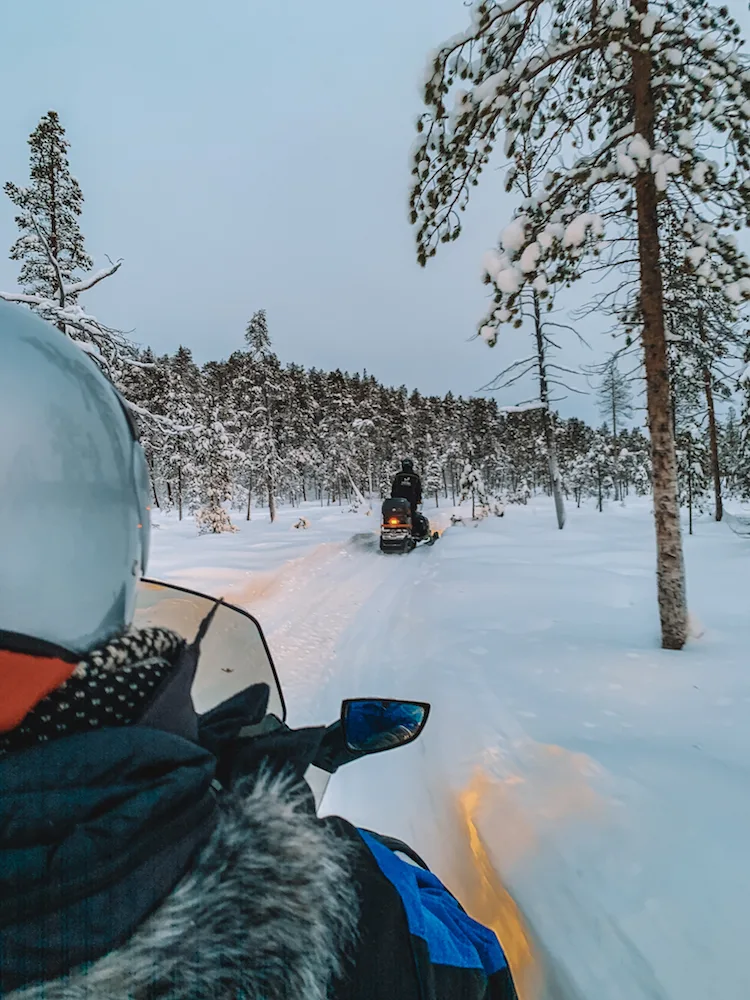 Driving a snowmobile through the snowy forests in Inari, Finland