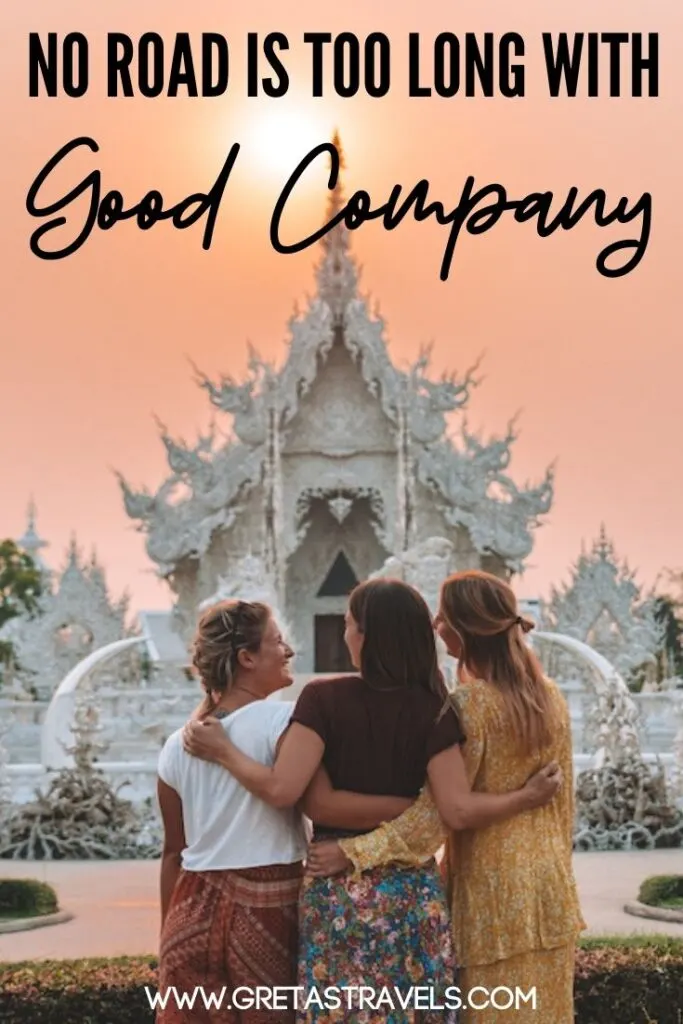Photo of three girls standing hugging each other in front of the White Temple in Chiang Rai, Thailand, with text overlay saying "No road is too long with good company" - one of my favourite quotes about travelling with friends!