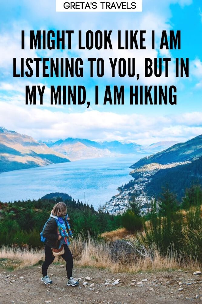 Photo of a blonde girl hiking up Queenstown Hill, with the town, lake and mountains behind her and text overlay saying "I might look like I'm listening to you, but in my head I'm hiking" - a funny hiking quote that can make a good hiking caption!