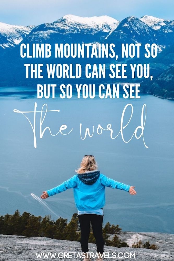 Photo of a blonde girl with a turquoise jacket standing with her arms open in front of the lake and mountain view at the top of Stawamus Chief Peak in Canada, with text overlay saying 