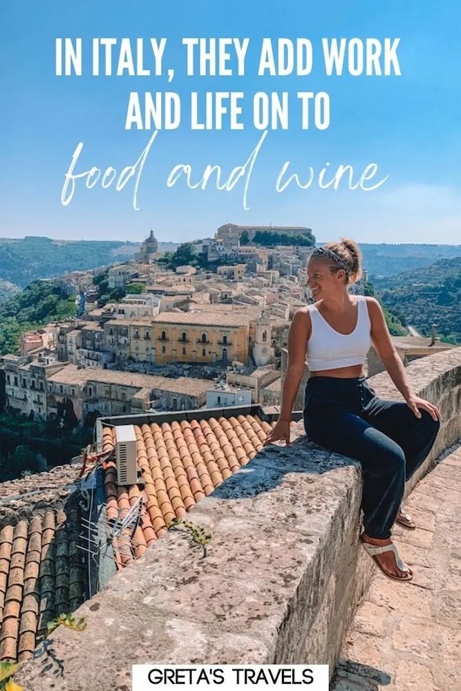 Photo of a blonde girl sitting on a rock ledge overlooking Ragusa in Sicily, Italy, with text overlay saying “In Italy, they add work and life on to food and wine.”