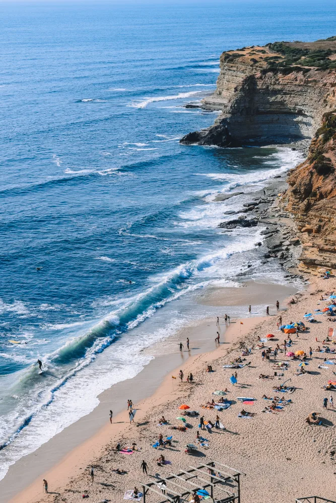 The surf waves of Praia de Ribeira d’Ilhas in Ericeira seen from above