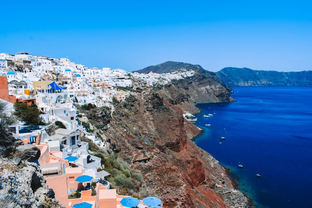 The white houses of Oia, Santorini, perched on top of its iconic black cliffs - the most famous place to stay in Santorini