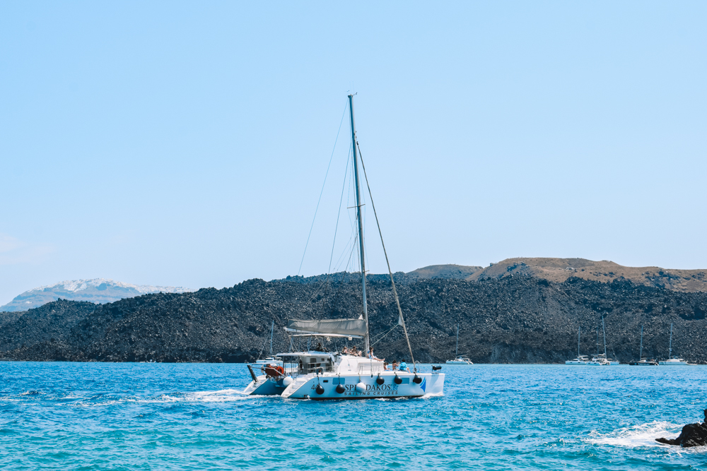 A catamaran cruising in Santorini, Greece - a popular activity on every Santorini itinerary