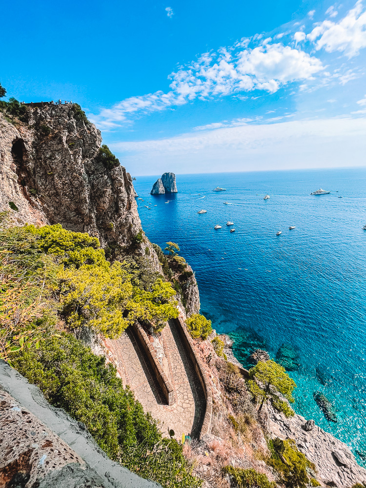 The iconic bends of Via Krupp, with the Faraglioni Rocks of Capri in the distance