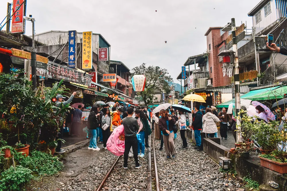 Crowds walking along train tracks at Shifen Old Street Taipei Taiwan with lanterns.