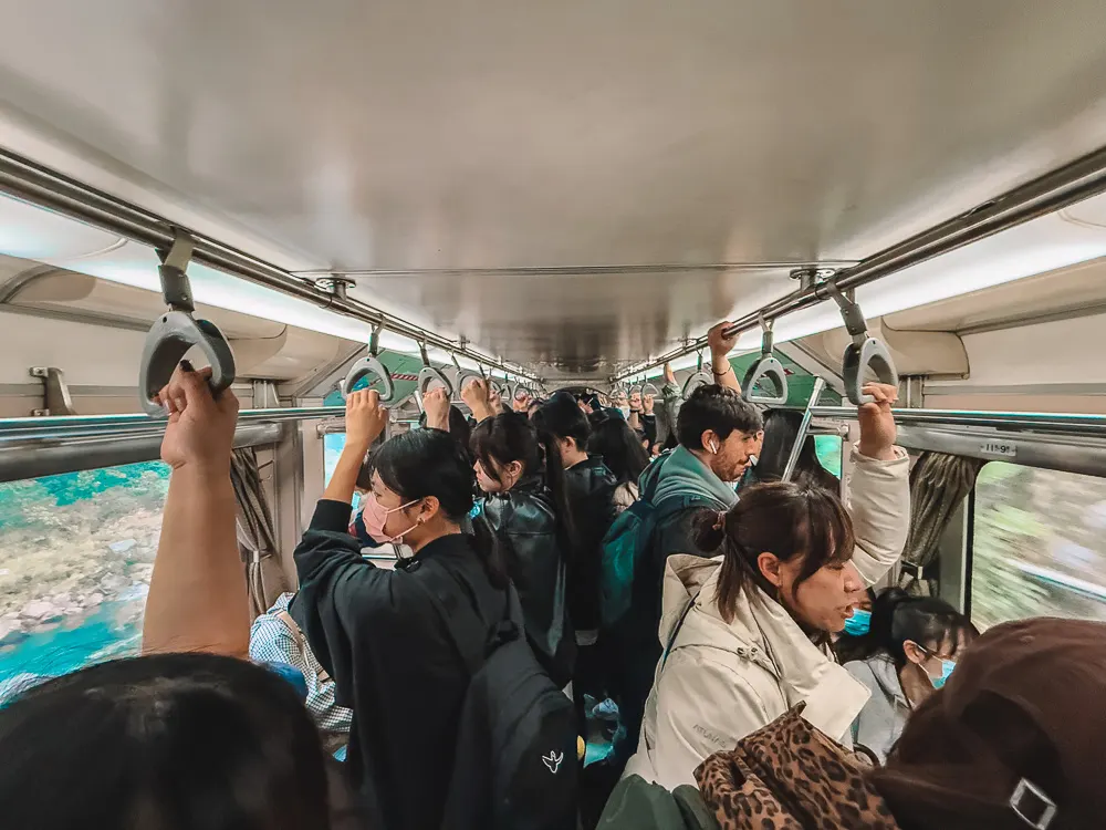 Crowded standing-room train from Taipei to Ruifang Taiwan with passengers holding handrails.